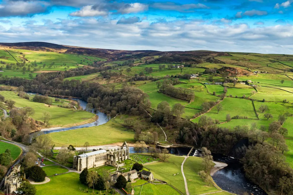 Aerial view of green fields and hills under blue sky