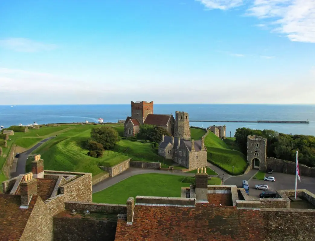 Stone buildings on grassy hill near body of water