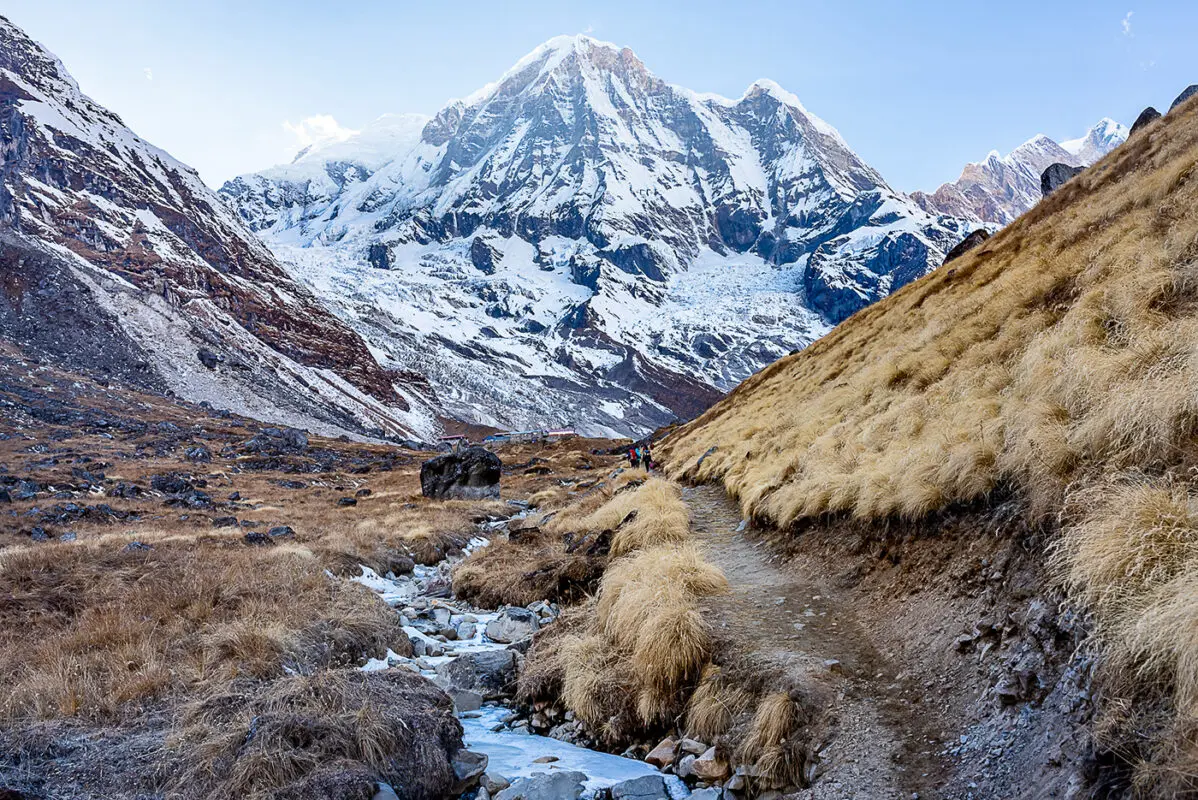 small mountain trail with snow covered peak in background