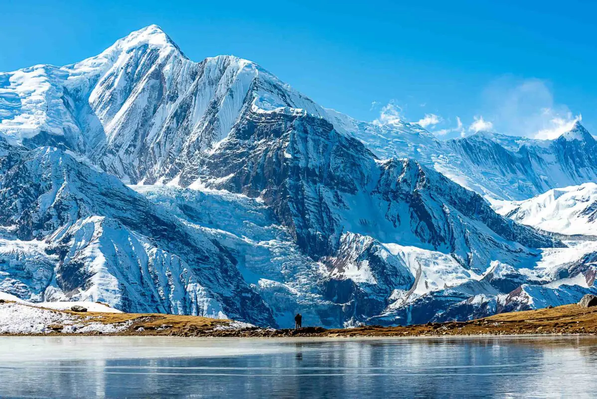 body of water with snow covered mountains in background