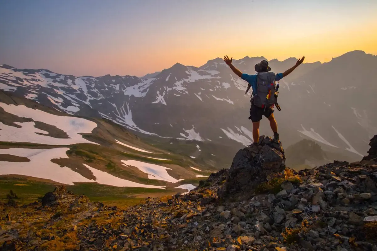 man standing on rock looking out over the mountains