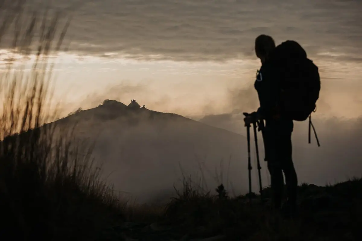 women with big backpack hiking in grassy field