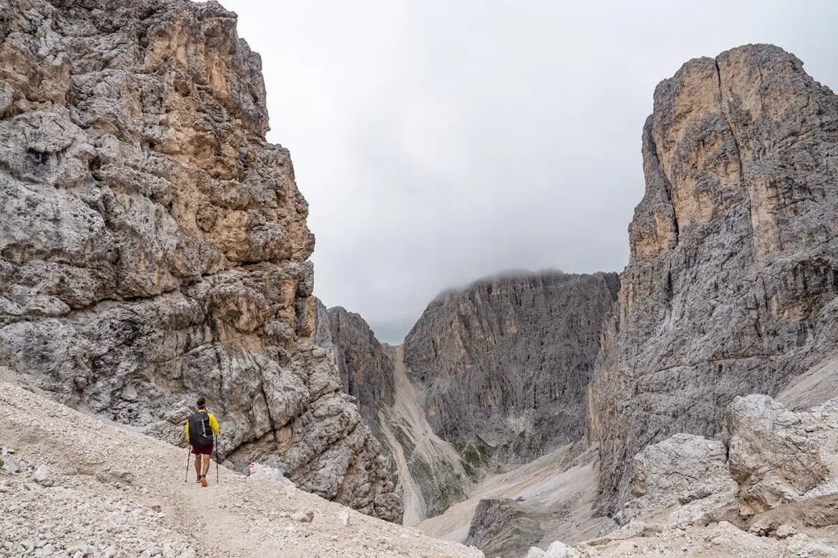 Person hiking in mountain valley surrounded by rugged peaks