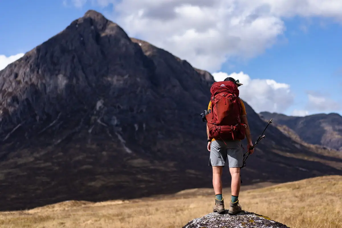 person with backpack standing on rock