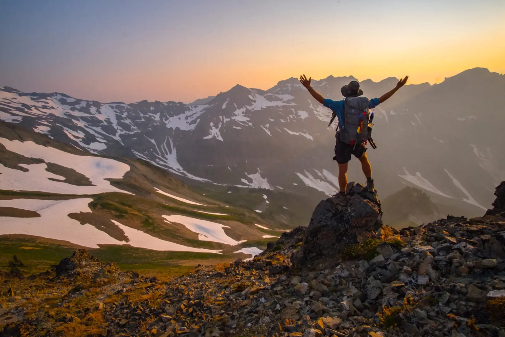 man standing on rock looking out over the mountains