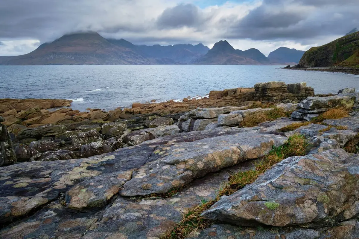 colored stones near the ocean with mountains in the background