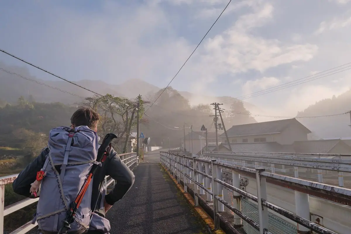 person with backpack walking over bridge