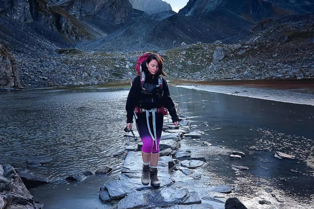 person hiking on stone path in shallow body of water