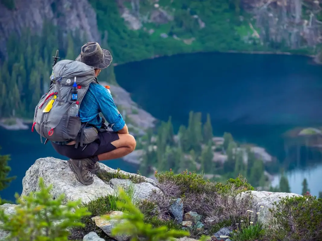 man sitting on rock looking out over mountain lake