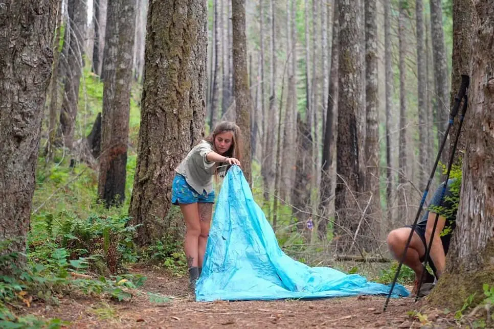 women setting up her tent in the forest