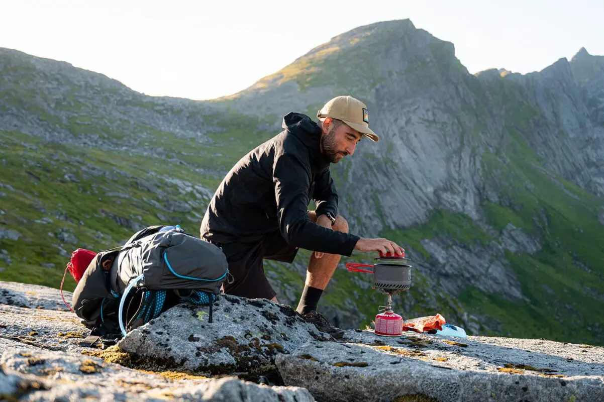 man boiling water on rocky surface