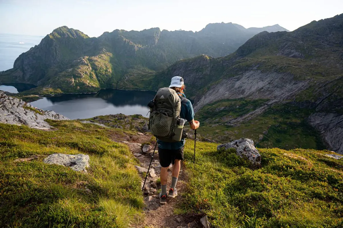 person hiking on small path towards body of water