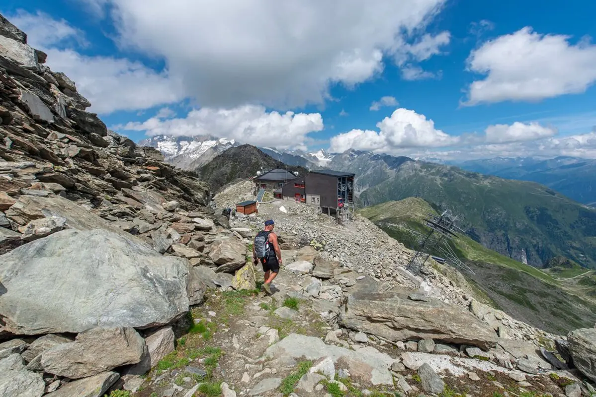 man hiking toward cable car on mountain top