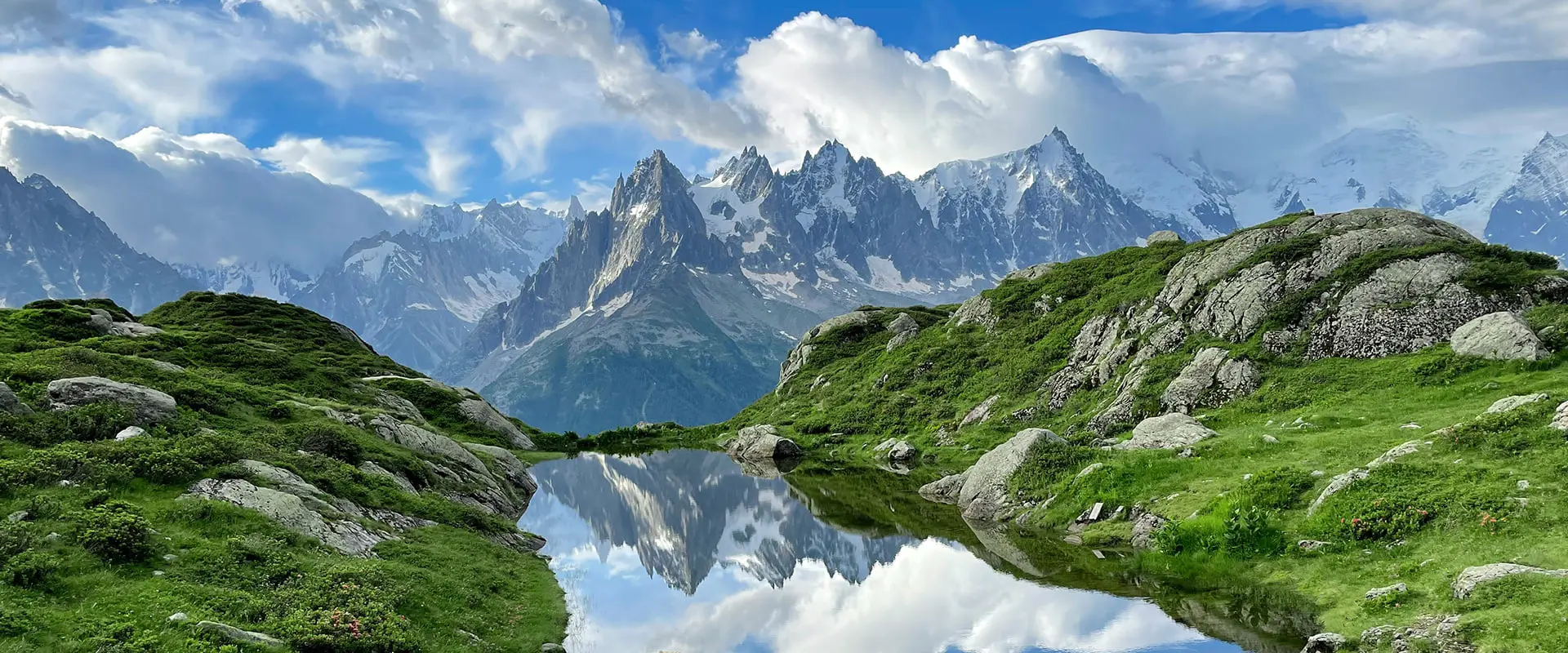 mountain lake between green landscape and mountains in background