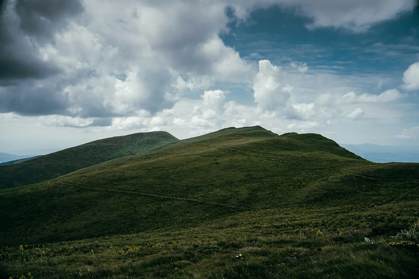 grassy hills during cloudy day