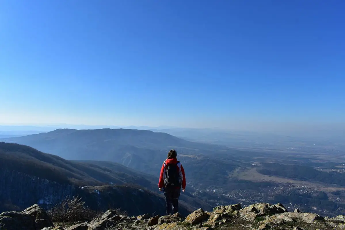 person standing on top of mountain looking out over city