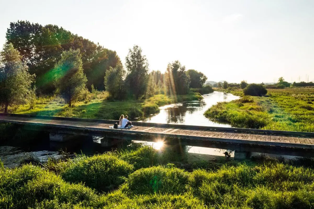 couple sitting on wooden bridge by a river