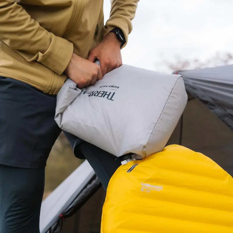 person inflating sleeping pad