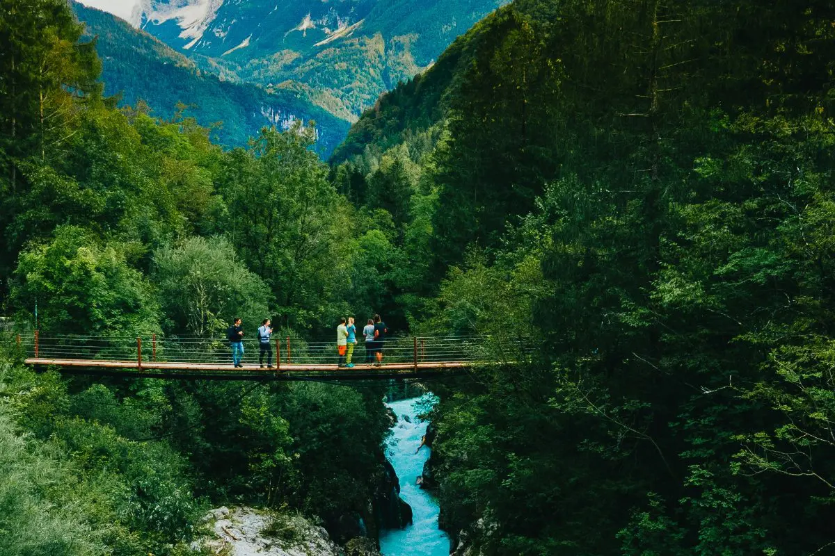 people on suspension bridge over blue river