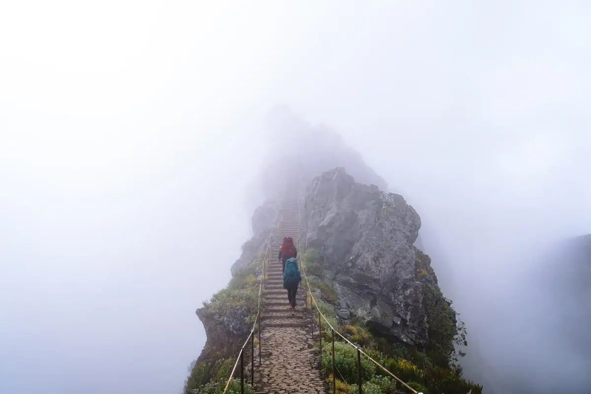 two persons hiking up stone staircase in the clouds on madeira island