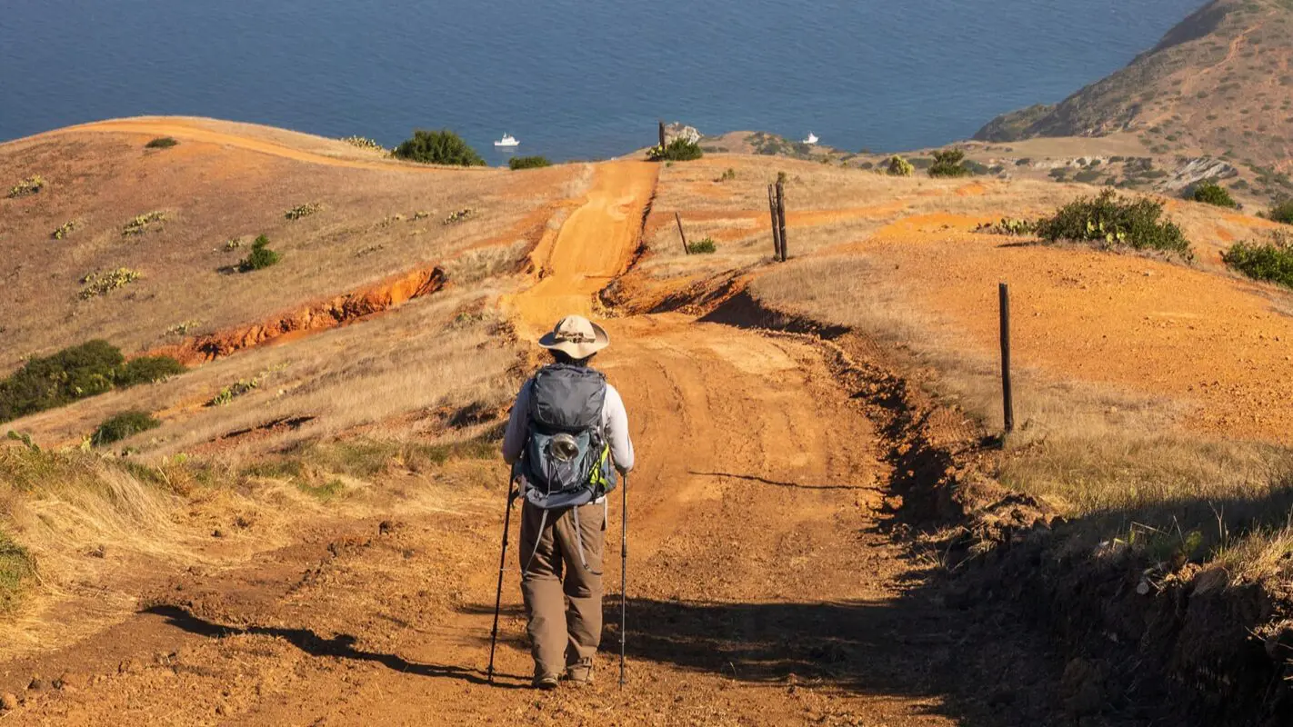 man hiking on dirt road towards the ocean on the island of Catalina