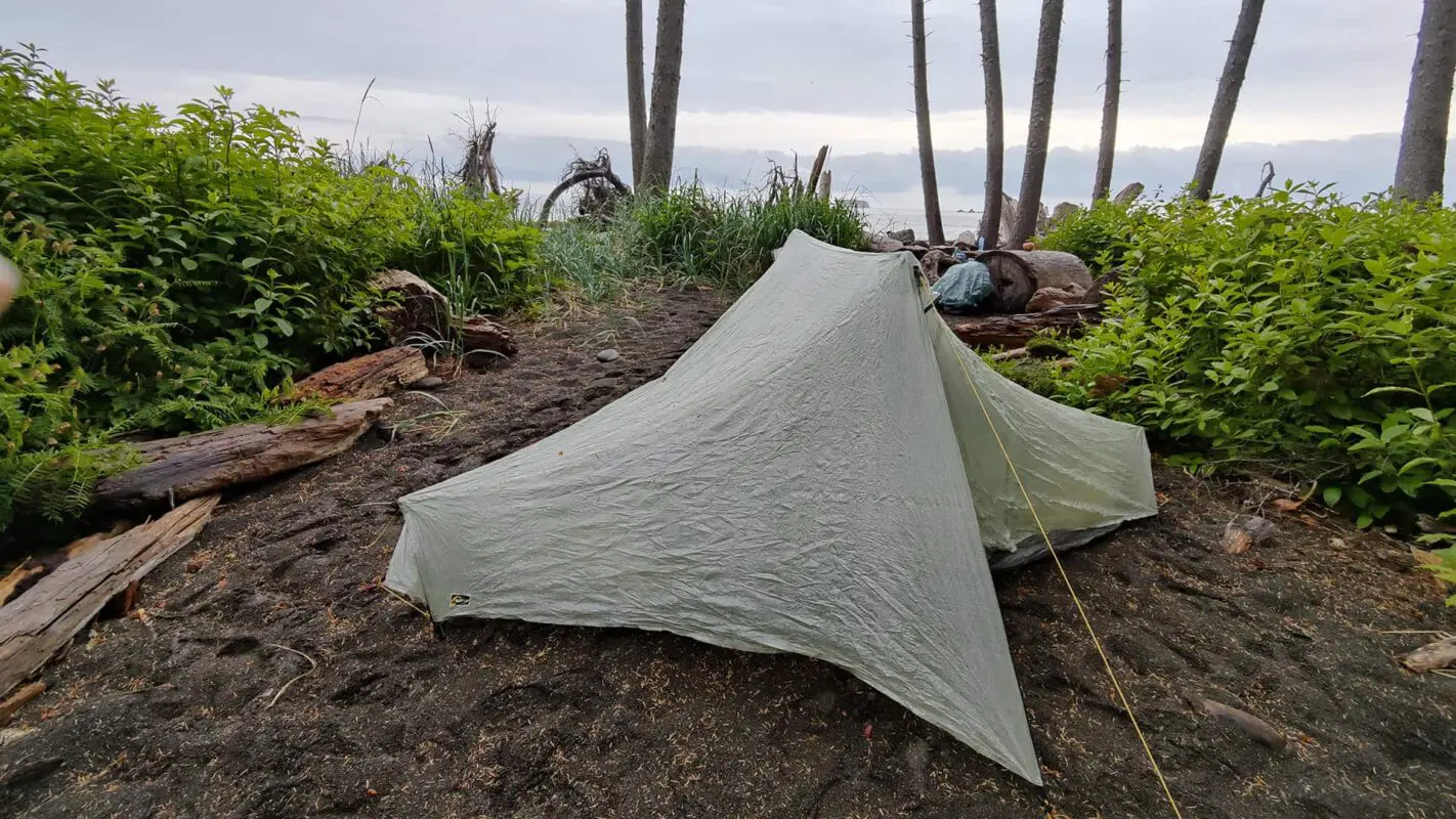 tent pitched near trees and body of water