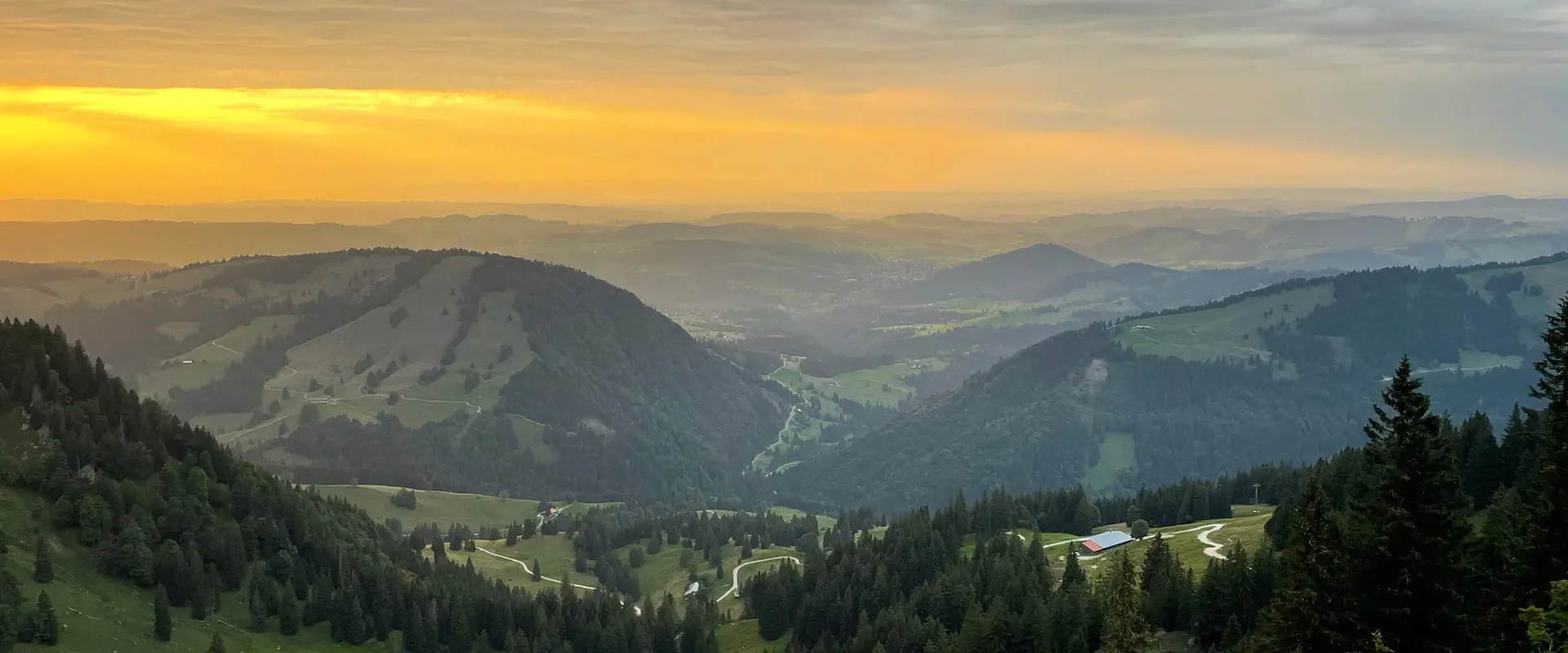 set of green hills in the distance during sunset in the German alps