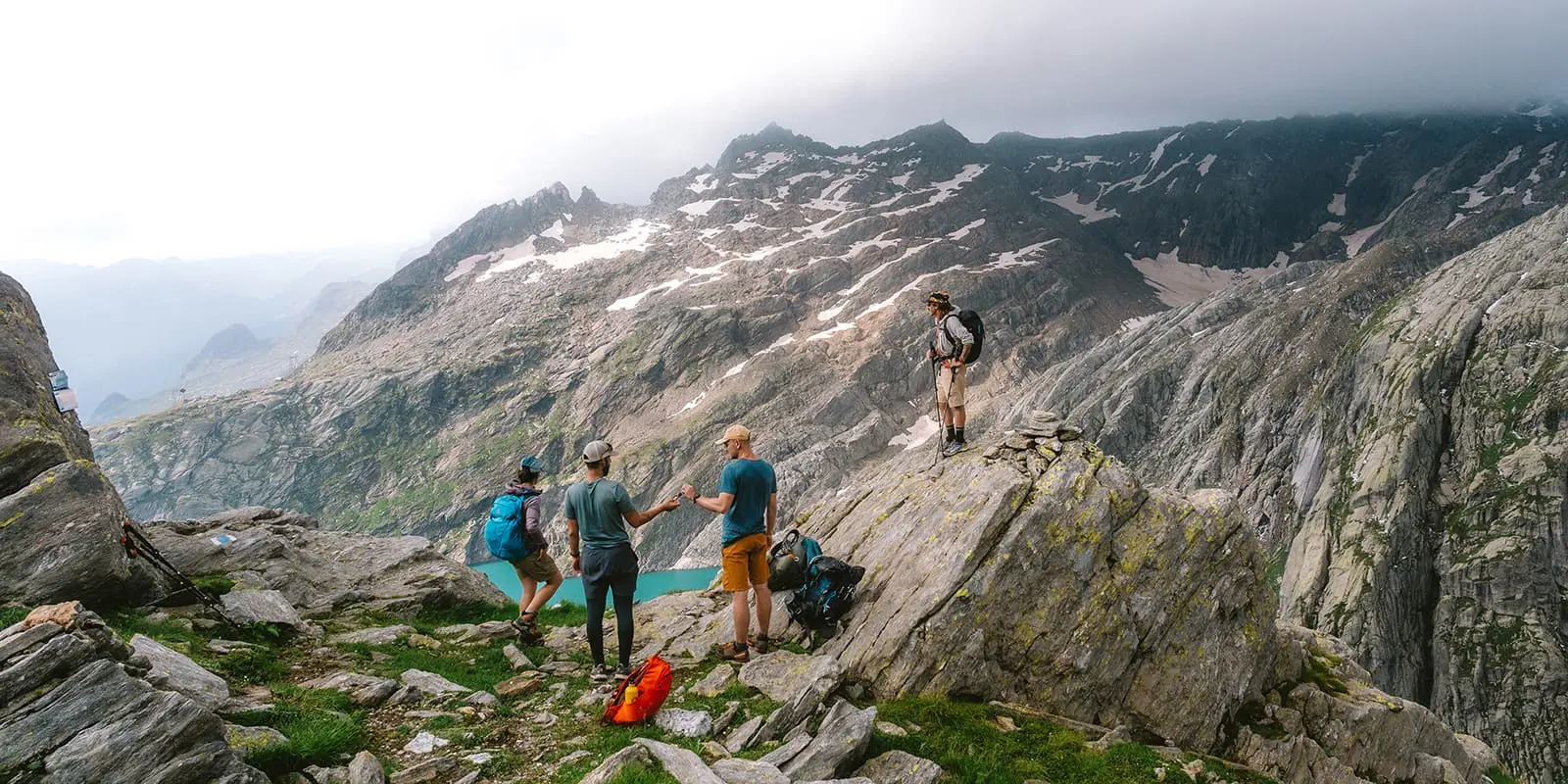 group of people on mountain peak overlooking mountain lake