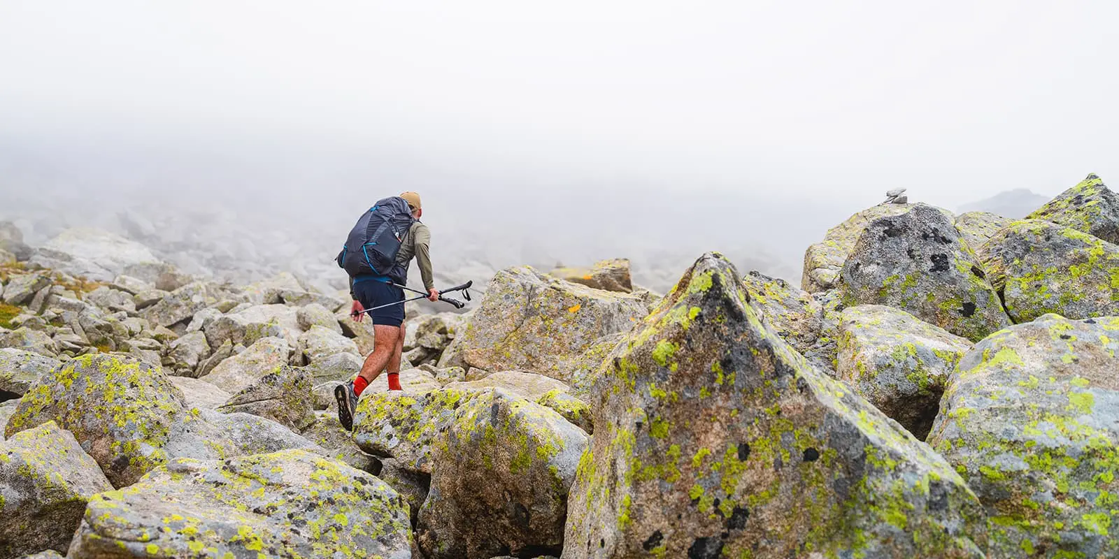 man hiking on big boulders on the Carros de Foc