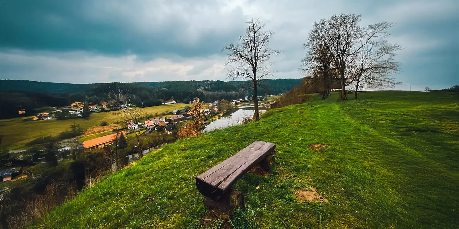 wooden bench on hill looking out over small town near river in Czech republic