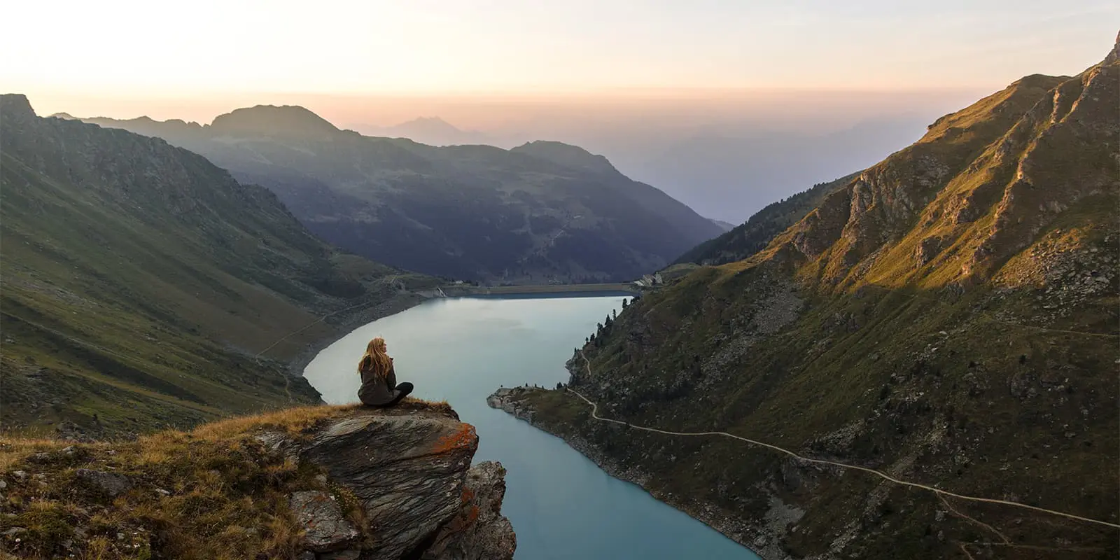 women sitting on rock overlooking an alpine lake in Switzerland