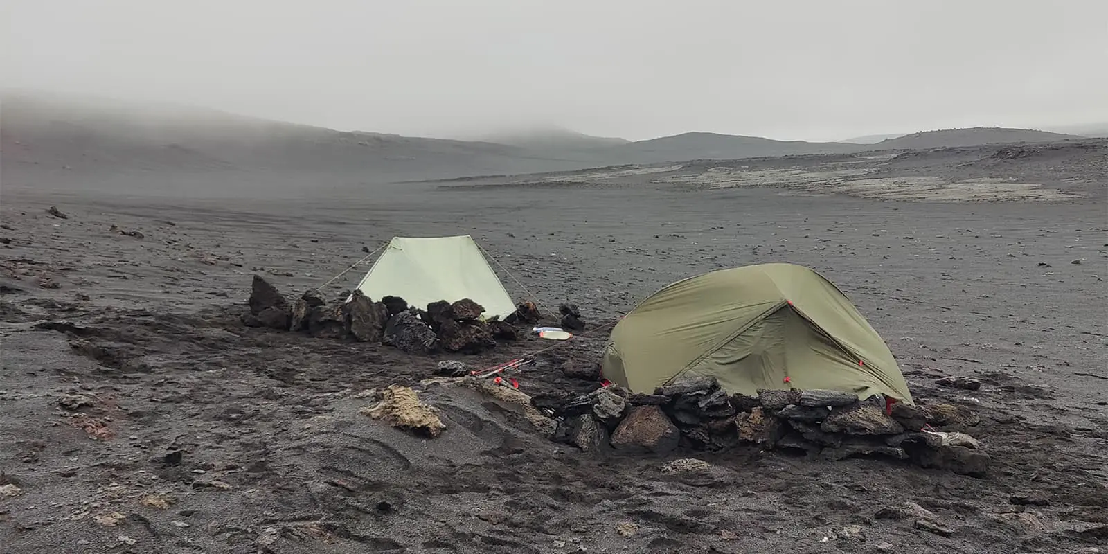 two tents pitched on black sand plain in iceland