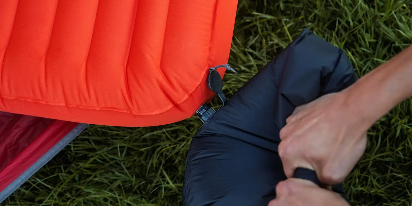 person pumping up sleeping pad with pump sack