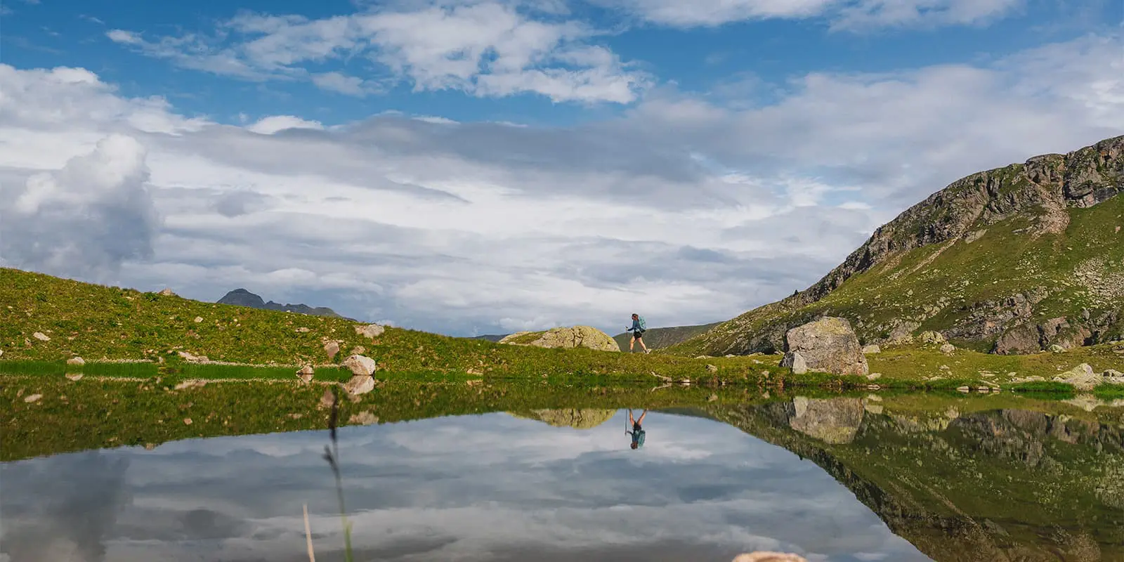 person hiking near body of water in the Italian alps