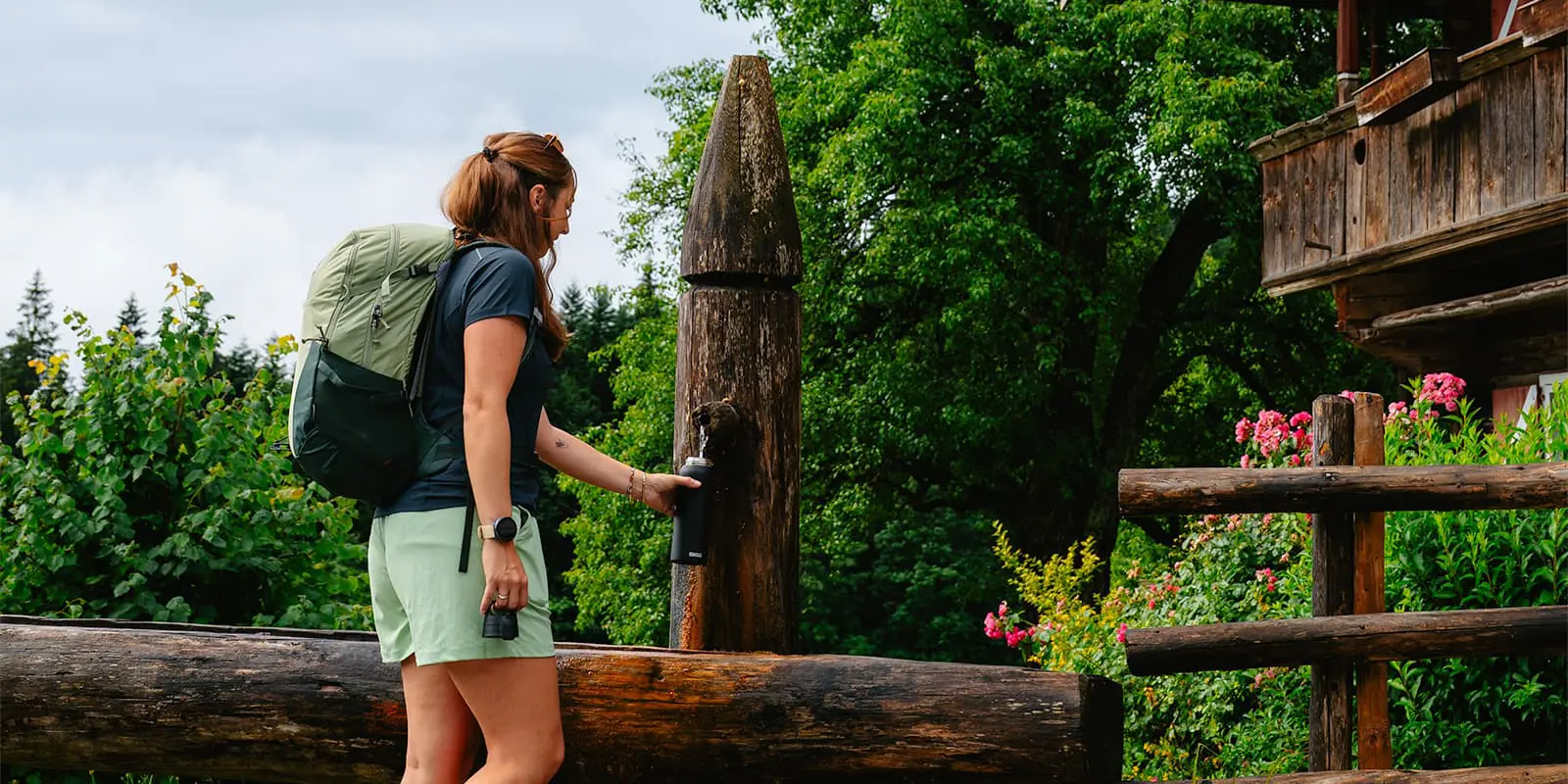 hiker filling bottle with water from outside stream in the Austrian Alps