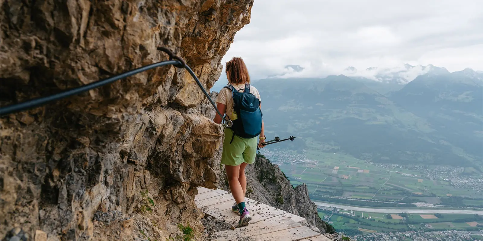 person hiking on narrow wooden walkway on the Fürstensteig in Liechtenstein wearing a Deuter Speed Lite backpack