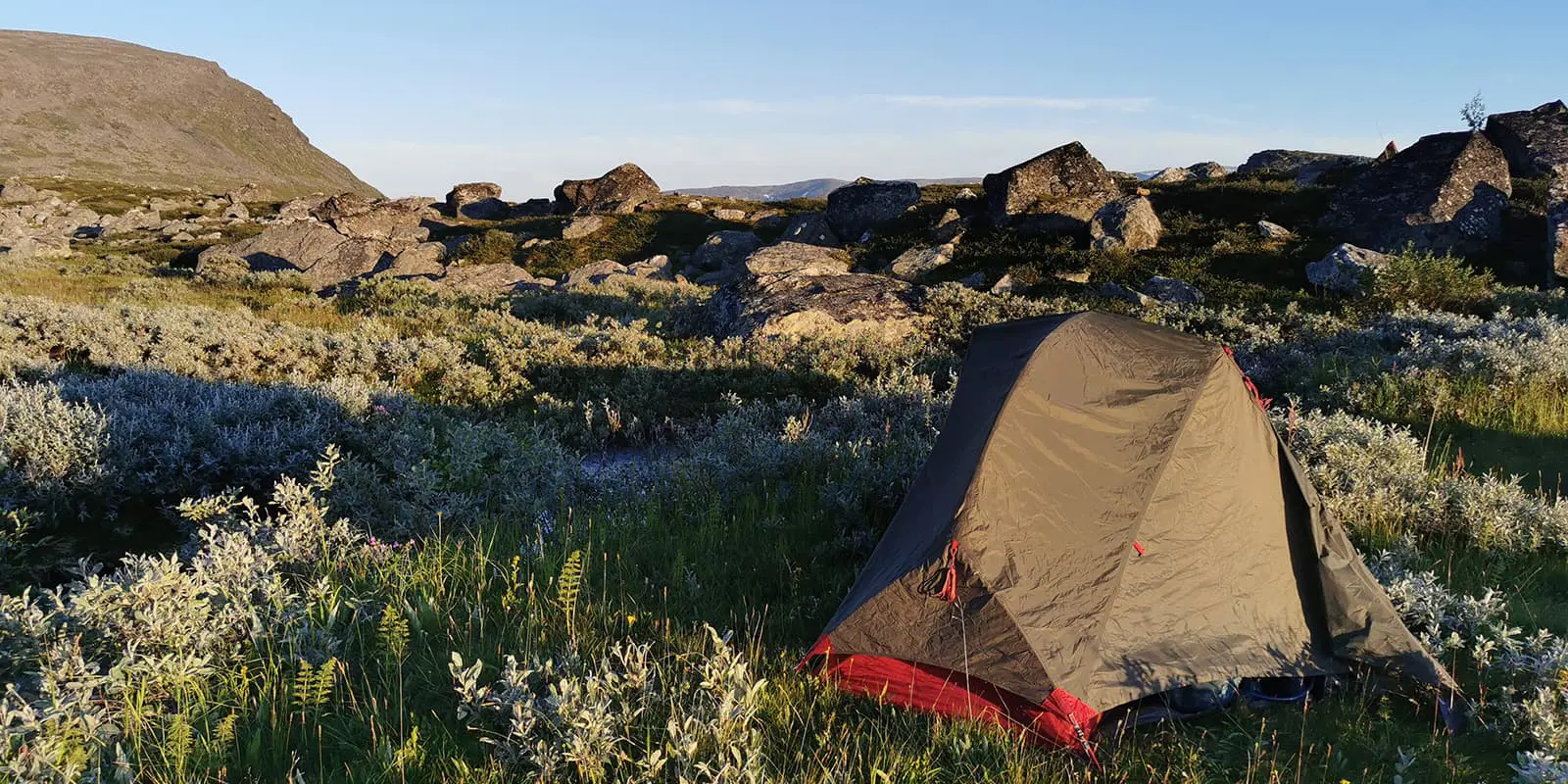 MSR tent in field with big boulders and hills in the background