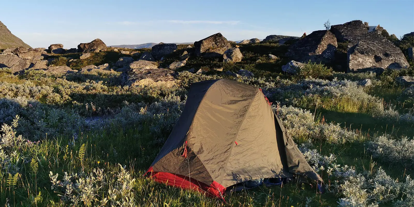 MSR tent in field with big boulders and hills in the background