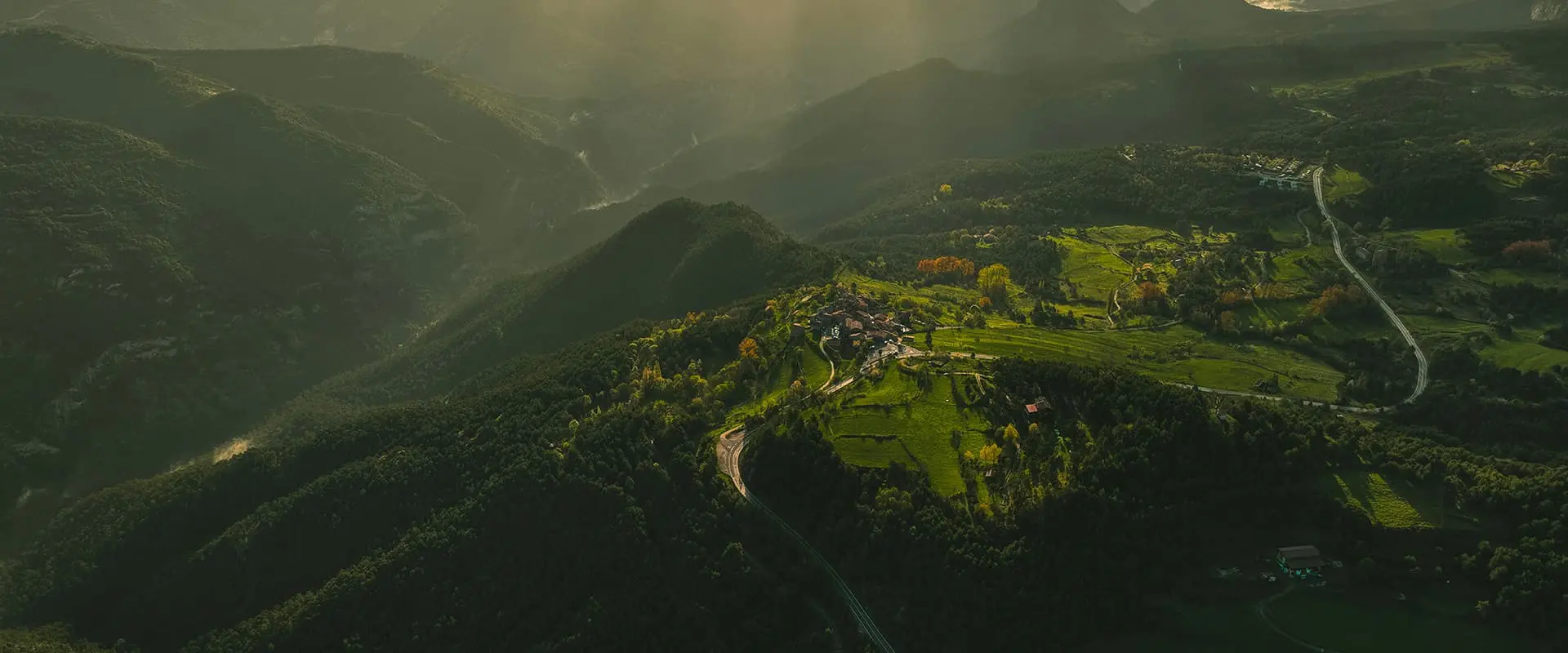 sunlight shines over a mountainous landscape in de Saldes valley