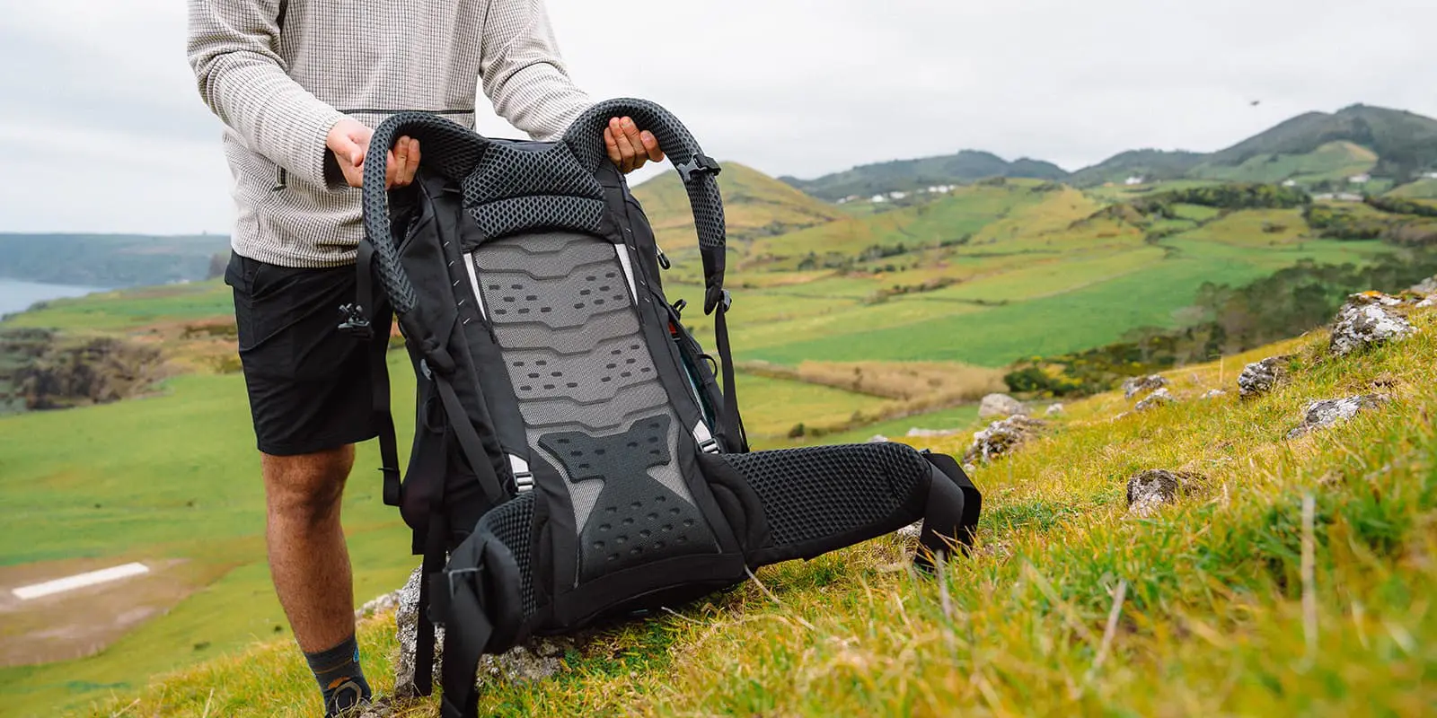 person putting his osprey backpack in the grass