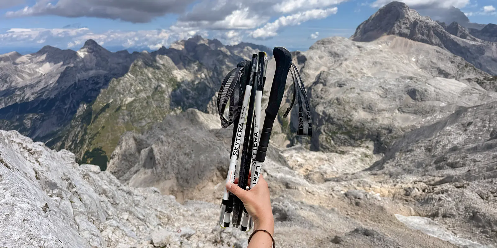 person holding hiking poles with mountains in background