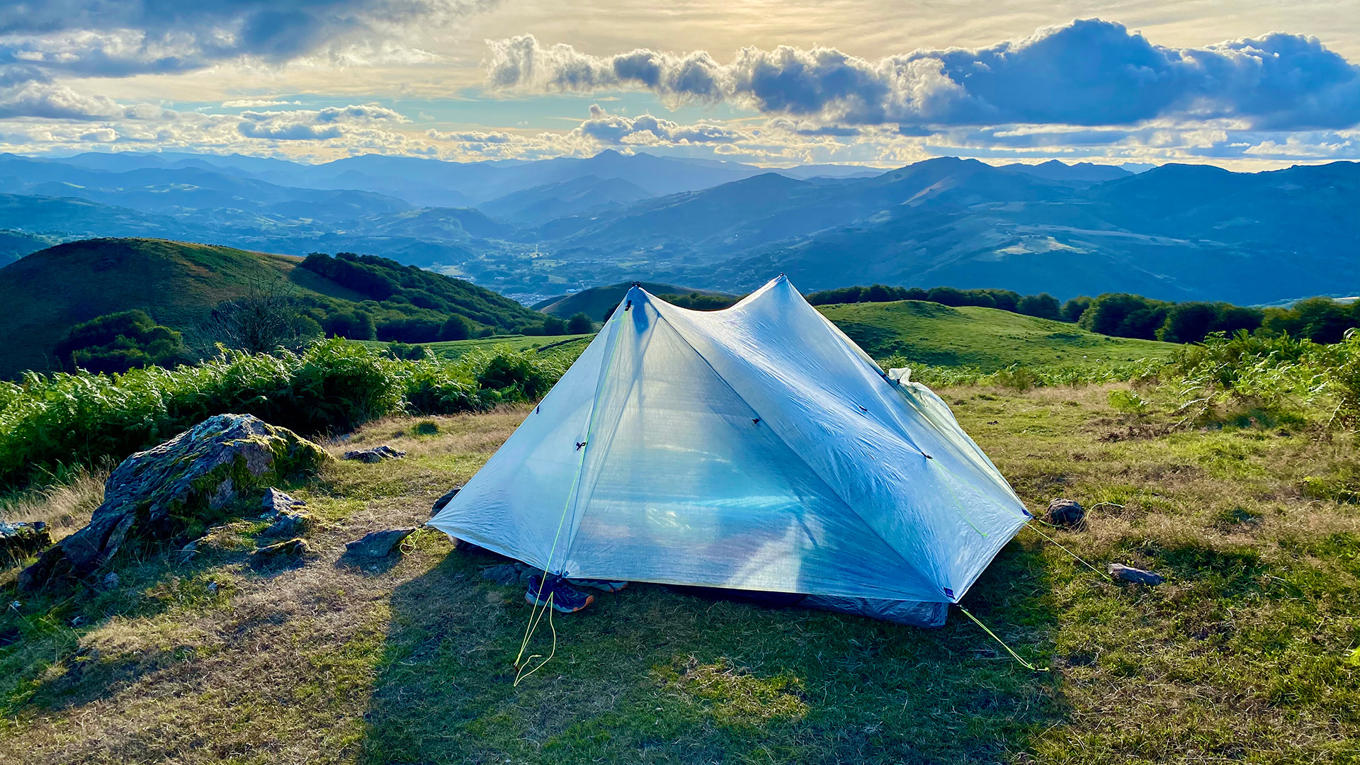 Tent on grassy surface with mountains in the background