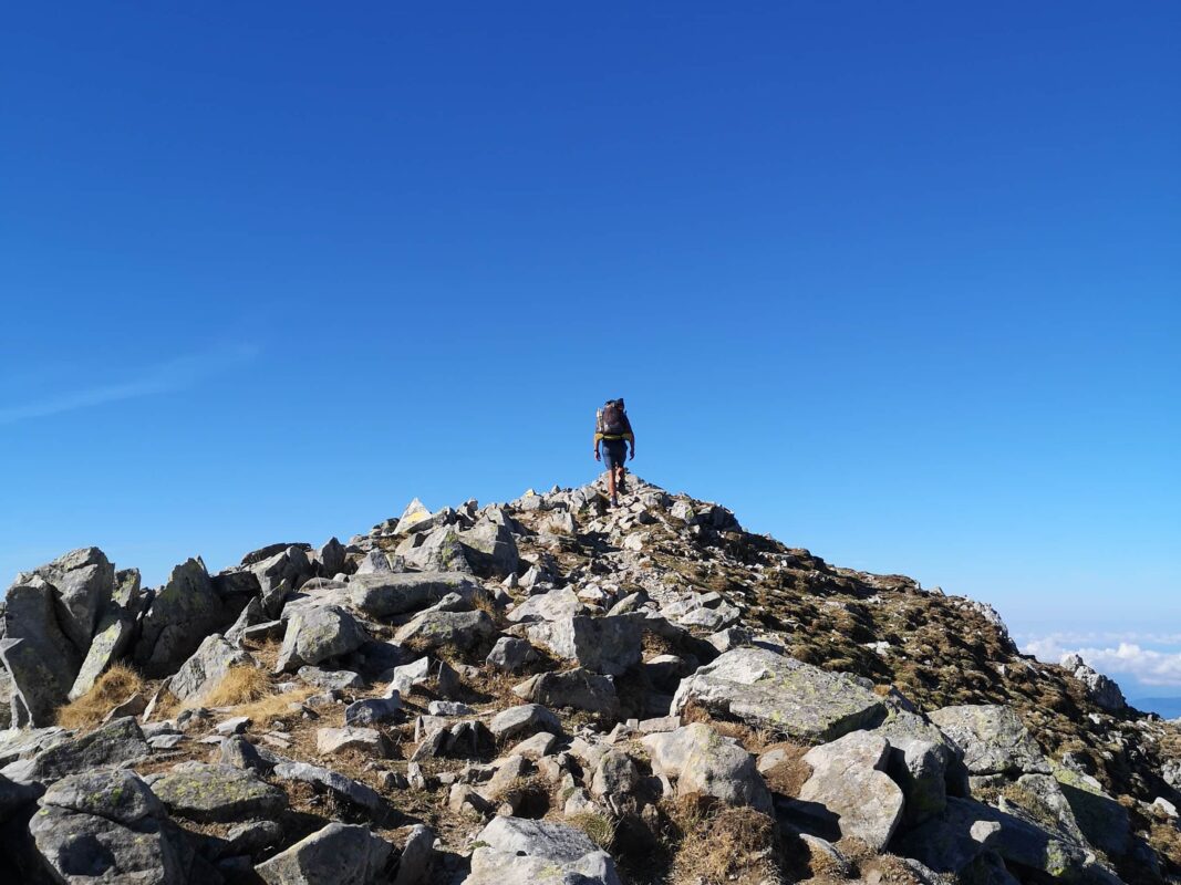 Man hiking on rocky surface on the GR20 in Corsica, blue sky