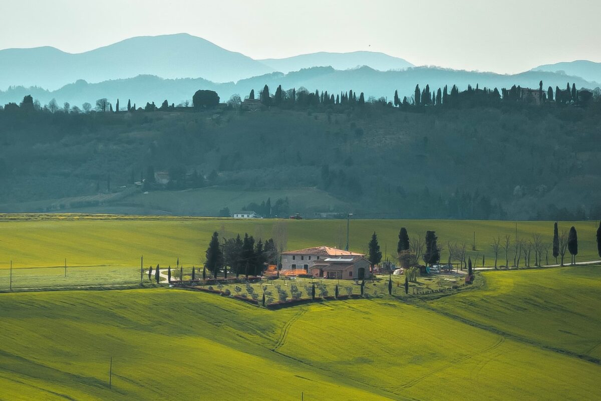 House in the countryside of Tuscany, Italy. Green field with mountains in the background