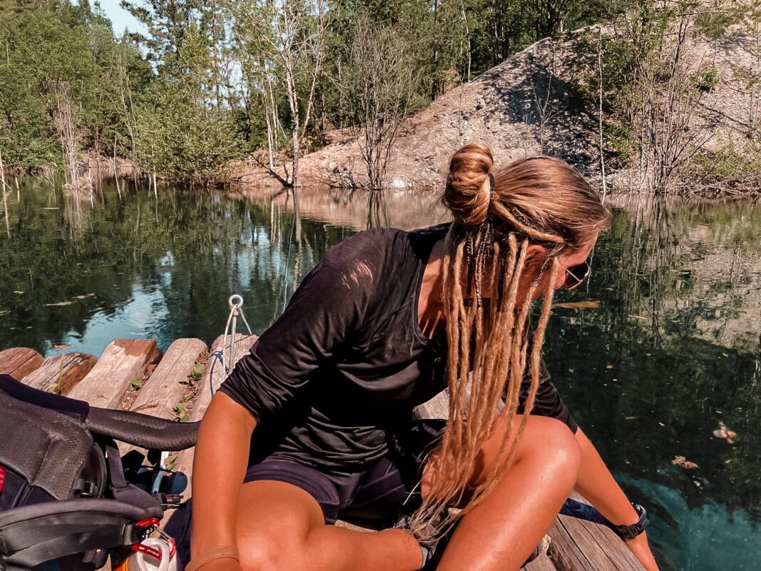Women with long blond hair having a break near a river on a wooden plateau.