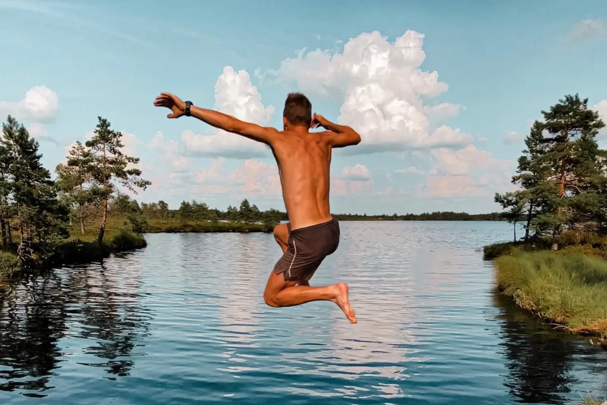 Man jumping into lake on sunny day in Estonia