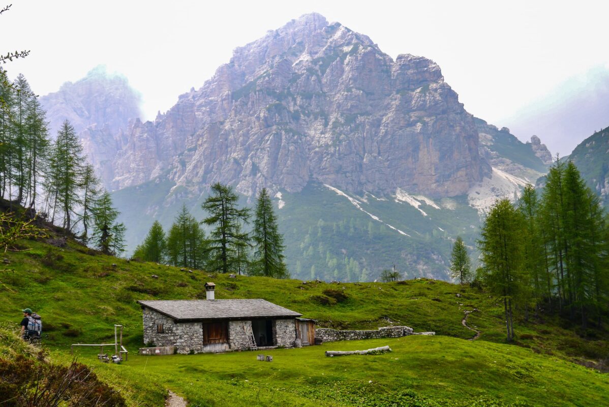 Small mountain shelter made of stone with Dolomites mountains in the background