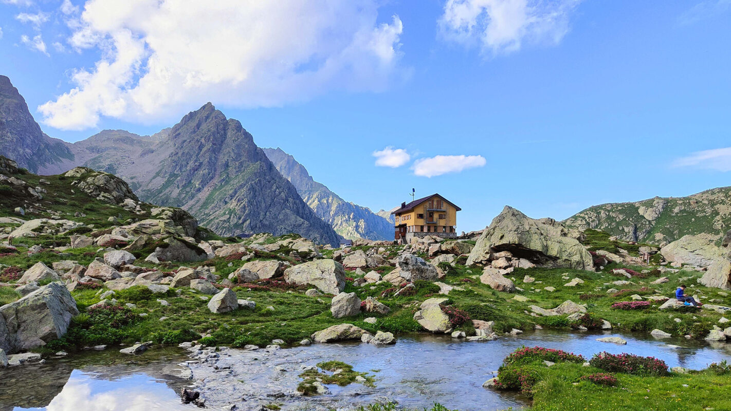View of mountain hut with river in front and mountains in the background