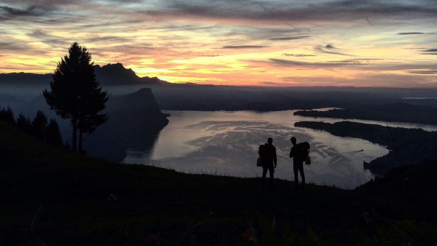 Silhouet of two hikers watching over lake Lucerne (Switzerland) during sunset