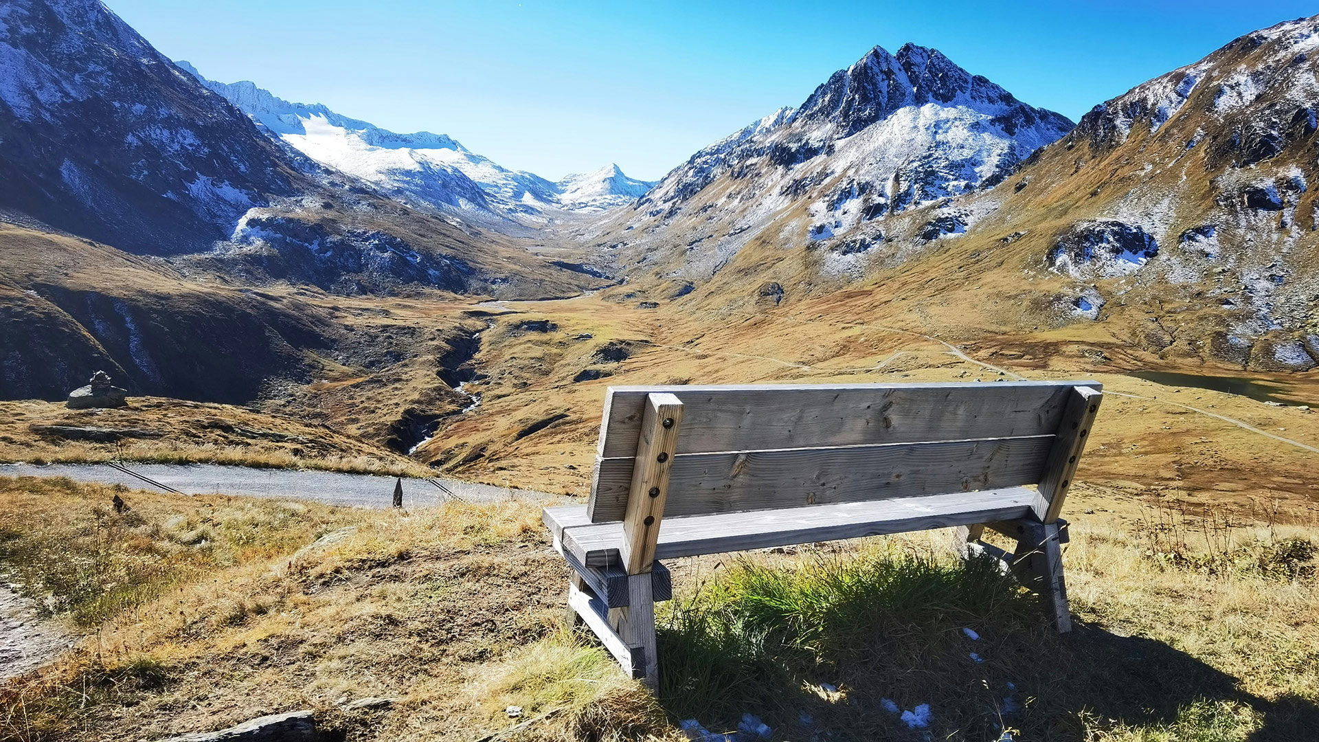 A wooden bench facing snow covered mountains near Andermatt, Switzerland